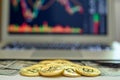 Gold bitcoins and dollar bills appearing from above a laptop with stock exchange charts on the screen