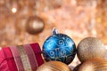 Gold and blue Christmas baubles and red box on the background of defocused golden lights. Royalty Free Stock Photo