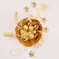 Gold bowl with christmas stars, balls, ribbons on white wood board, top view. Royalty Free Stock Photo