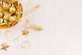 Gold bowl with christmas stars, balls, ribbons on white wood board, top view. Royalty Free Stock Photo