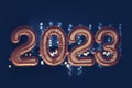 Gold, bronze inflatable foil balloons numbers 2023 on the window against the background the night city, in neon light Royalty Free Stock Photo