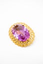 Gold brooch jewelry in the center of which is a purple stone