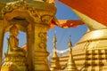 Gold Buddha statue in golden recess in front of gold stupa with orange buddhist flags waving and flying and blue sky background