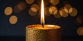 A gold candle with a flame is lit on a dark surface. Royalty Free Stock Photo
