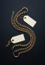 Gold chains with two blank tags on a dark black surface. The chains, featuring a Royalty Free Stock Photo