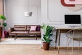 Gold chair at desk with desktop computer in open space interior with plant and sofa. Real photo Royalty Free Stock Photo