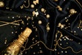 Gold Champagne bottle with confetti stars and party streamers on festive black background. Royalty Free Stock Photo