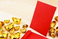 Gold Chinese ingot Yuan Bao and Blank red envelopes on wooden background