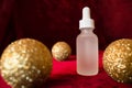 Gold christmas balls and face serum on red background Royalty Free Stock Photo