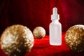 Gold christmas balls and face serum on red background Royalty Free Stock Photo