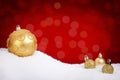 Gold Christmas baubles on snow with a red background Royalty Free Stock Photo