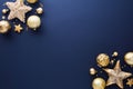 Gold Christmas decorations on dark blue background. Frame of sparkle Xmas stars and baubles. Flat lay, top view Royalty Free Stock Photo