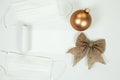 Gold Christmas tree bauble with white protective surgical mask on a white background. Christmas 2020 with the danger of Royalty Free Stock Photo