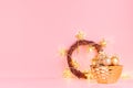 Gold Christmas wreath with glowing stars lights, balls, present on elegant pastel pink background. Royalty Free Stock Photo