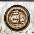 Gold circular insignia with engraving of tall ships on the wall in the St Petersburg Metro, Russia Royalty Free Stock Photo