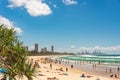 People relaxing on Burleigh beach with view of Gold Coast skyscrapers