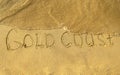 Gold Coast words written on beach sand with water wave