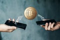 Gold coin Bitcoin payment from phone to phone, hands and TVs close-up. The concept of crypto currency. blockchain technology Royalty Free Stock Photo