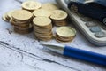 Gold coins, calculator, blue car toy and pen on wooden background. Selective focus on coins. Royalty Free Stock Photo