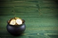 Gold coins in caldron for st. patricks day on green wooden background