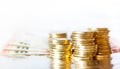 Gold coins piled up and euro bills on white background