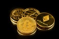 Gold color physical coins of common crypto currencies in bright light on black mirror surface