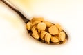 Gold color spoon full of round vitamin pills Royalty Free Stock Photo