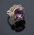 Beautiful large purple shining gemstone ring photo with gold colored band on a black shiny surface Royalty Free Stock Photo