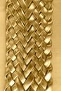 Gold-colored braided leather belt. Metallic shiny. Detail, texture, close-up