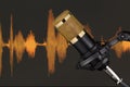 Gold colored condenser microphone over waveform