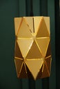 Gold-colored metal pendant lamp on green wall background, lampshade close-up