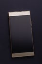 Gold colored smartphone with blank screen closeup flat on black background, top view Royalty Free Stock Photo