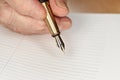 Gold coloured fountain ink pen in senior woman hand about to write something on empty daily planner page, closeup detail