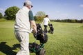 Gold couple walking on fairway with bags.