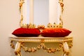 Gold crowns inlaid with red and blue precious stones, on red pillows, on an antique dressing room mirror. Royalty Free Stock Photo