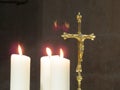 A gold crucifix stands beside lit white candles in a church Royalty Free Stock Photo