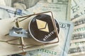 Gold cryptocurrency coin ethereum in mousetrap on pile of cash.