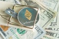 Gold cryptocurrency coin ethereum in mousetrap on pile of cash. Royalty Free Stock Photo