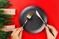 gold cutlery with black handles crossed over black plate on red table, the concept of New Year dinner Royalty Free Stock Photo