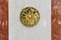 Decoration in the shape of a flower on a marble slab. Volumetric, shiny, carved, beautiful engraving on a white-brown stone wall.