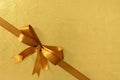 Gold diagonal corner gift bow ribbon, shiny metallic foil paper background Royalty Free Stock Photo