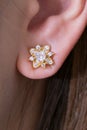 Gold earrings with diamond-shaped flowers on the white background Royalty Free Stock Photo