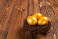 Gold eggs on nest on wooden background Royalty Free Stock Photo