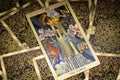 Gold embossed tarot cards on the table. The Major Arcana card The Tower lies facing the viewer.