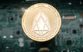 Gold eos coin, on background of computer motherboard