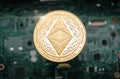 Gold etherum classic coin, on background of computer motherboard