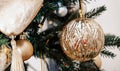 Gold festive decorations ballson the Christmas tree and beautiful yellow bokeh of glowing garland.