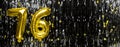 Gold foil balloon number number 76 on a background of black tinsel decoration. Birthday greeting card, inscription