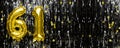 Gold foil balloon number number 61 on a background of black tinsel decoration. Birthday greeting card, inscription sixty