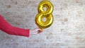 Gold foil balloon numeral 8 in femine hand. Happy Womens Day , copy space